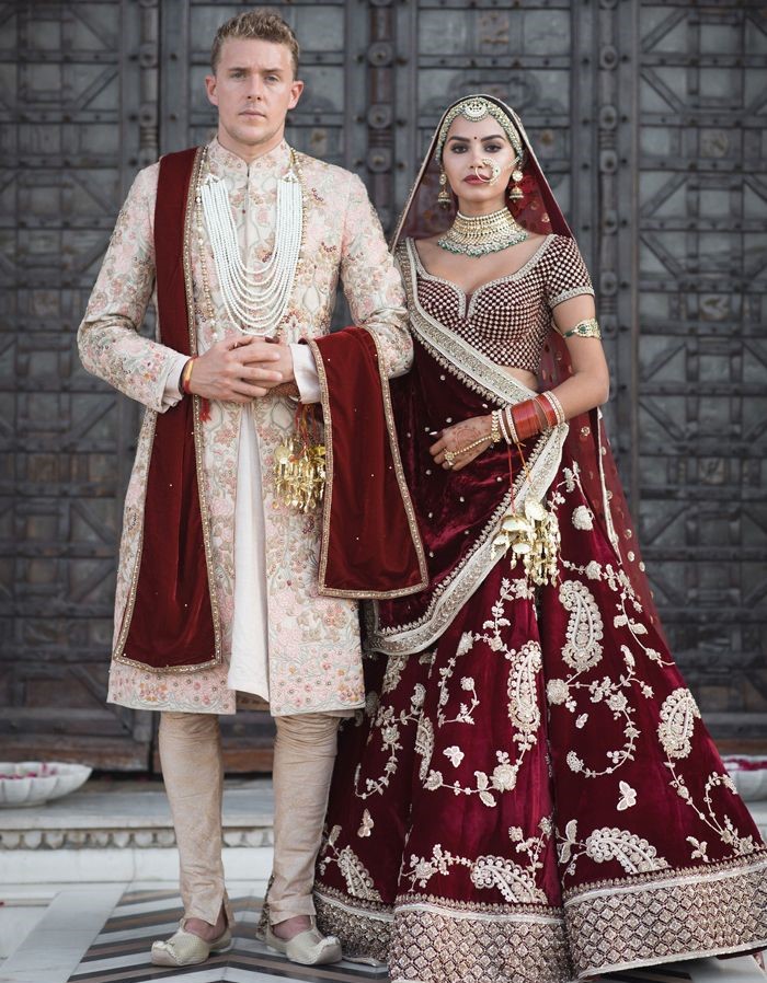 Bride and groom wearing maroon and gold coordinated royal wedding outfits for traditional Indian wedding inspiration