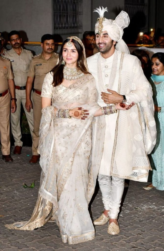 Alia Bhatt and Ranbir Kapoor are wearing elegant ivory and gold coordinated wedding outfits for modern Indian wedding inspiration